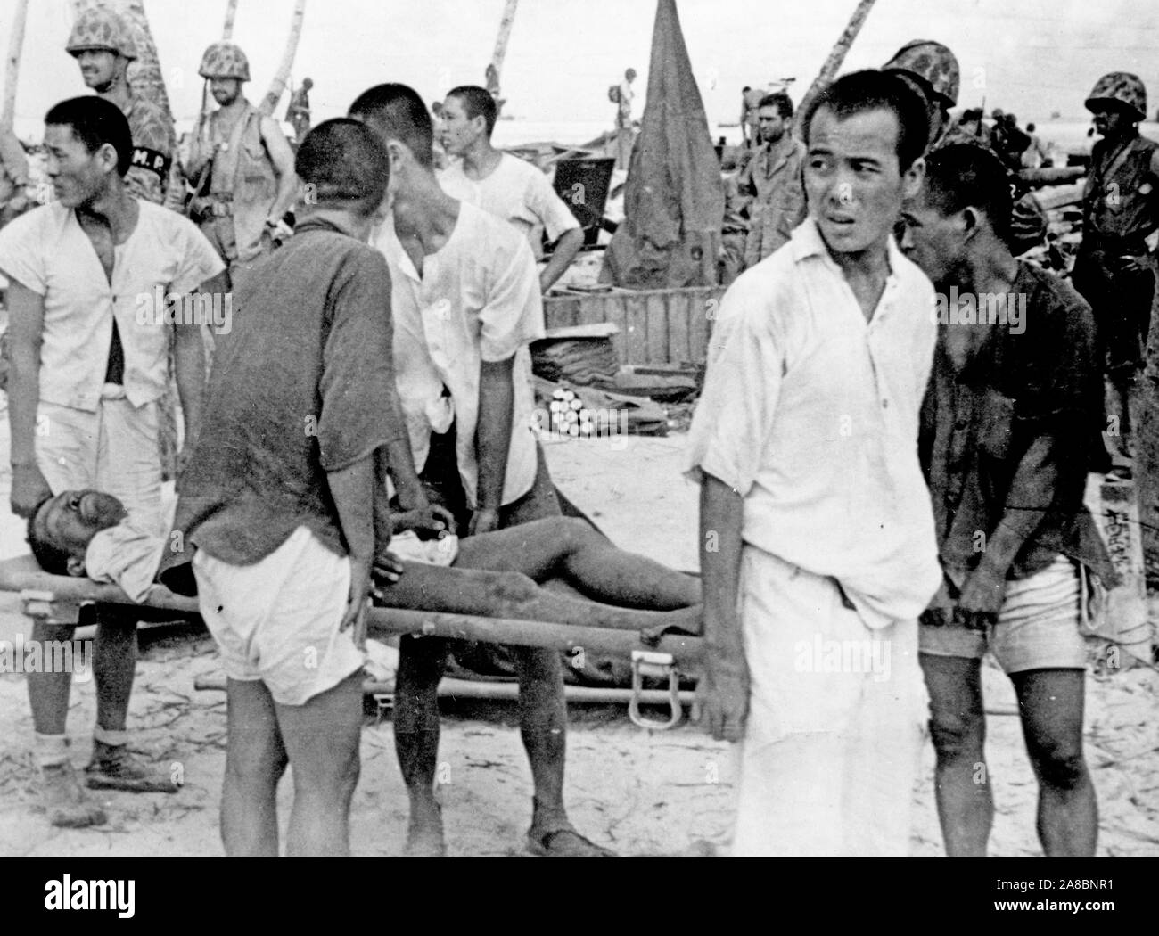 Los trabajadores coreanos utilizados por los japoneses para construir las defensas de la isla llevan a un compañero herido a recibir tratamiento - en Tarawa. Foto de stock