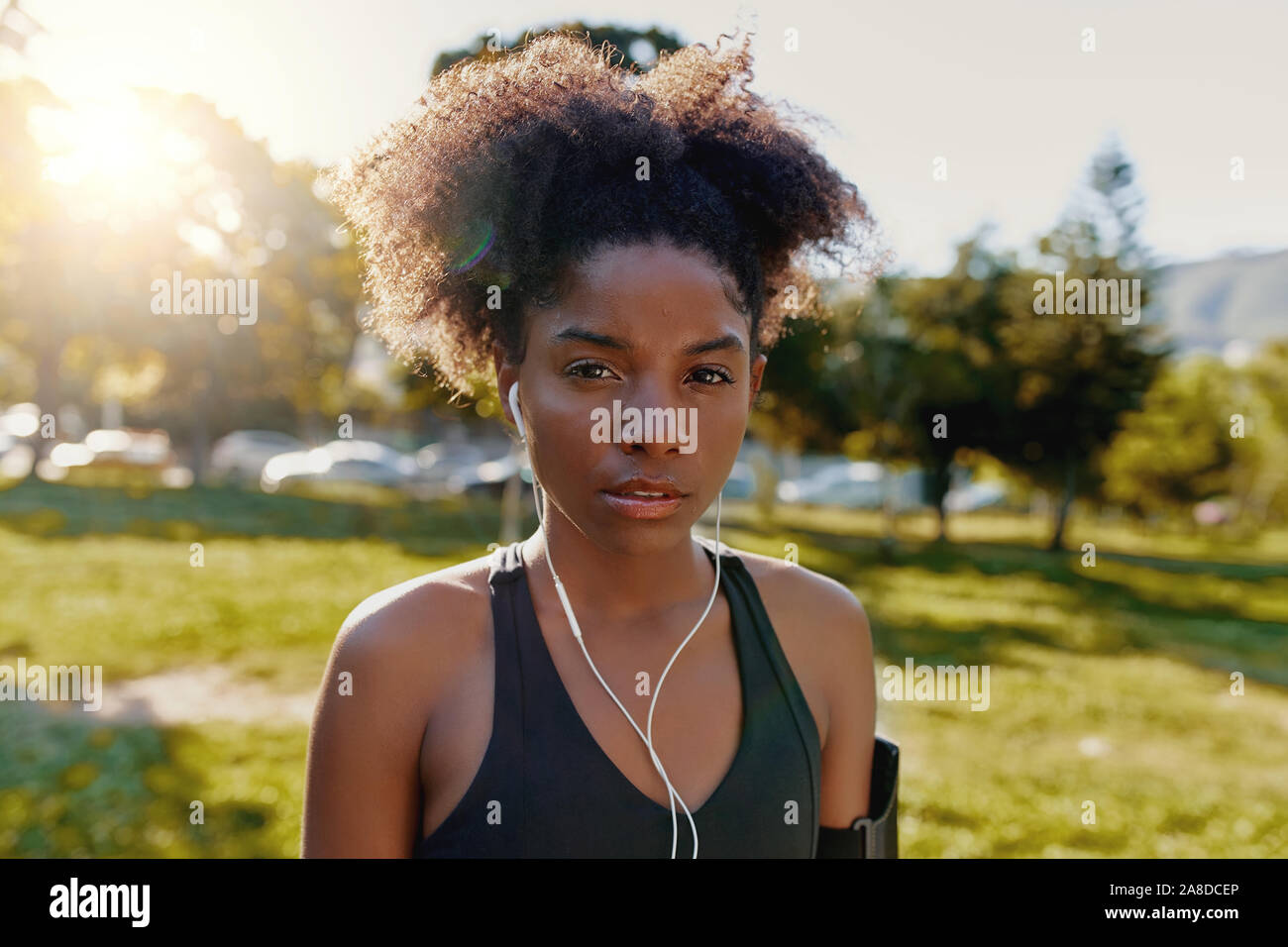 Retrato de un joven afroamericano deportivo con los auriculares en las orejas escuchando música mirando a la cámara - determina la aptitud de la mujer negra en Foto de stock
