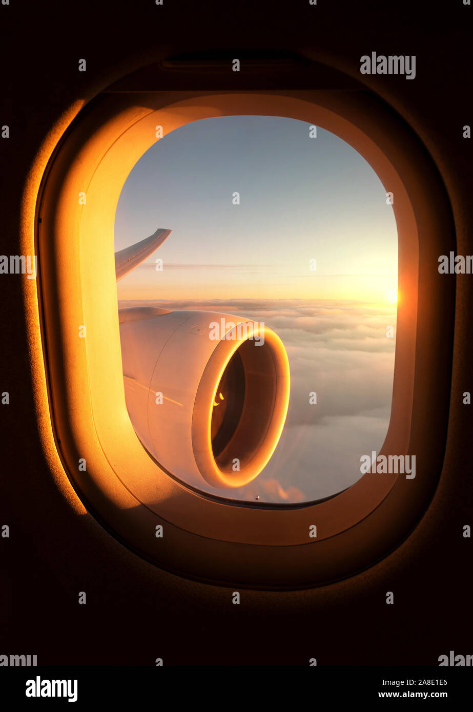 Impresionante puesta de sol vistos a través de la ventana de un avión con el jet del ala y el motor visible. Foto de stock