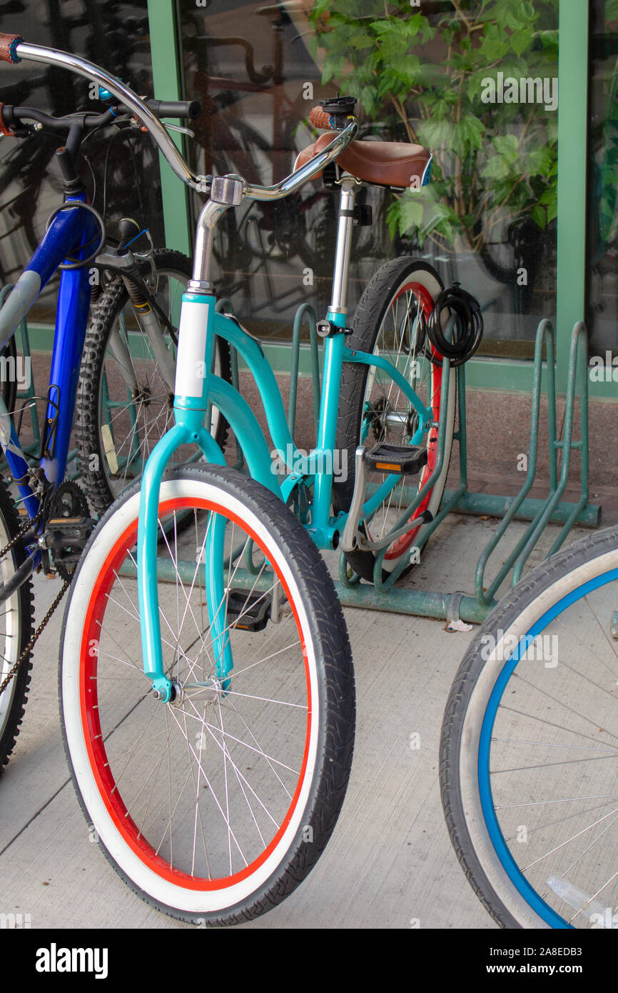 Una bicicleta de color Trendy Teal es encadenados entre otras bicicletas en un estante fuera de un edificio. Tiene forro blanco y rojo en sus neumáticos y una vendimia Foto de stock