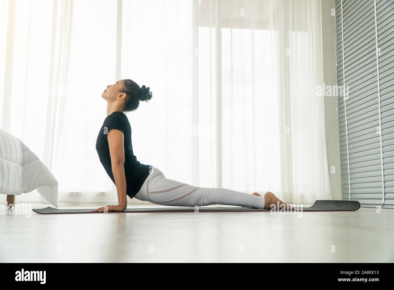 La mujer de mediana edad hacer yoga en el dormitorio en la mañana, muja, svanasana adho pose. Concepto de ejercicio y descanso en la mañana. Foto de stock