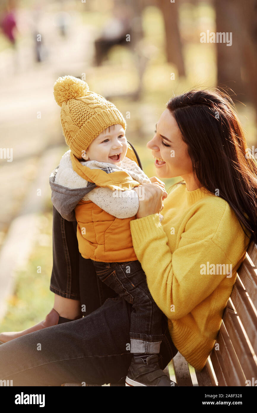 La madre y el bebé se sientan en un banco Foto de stock