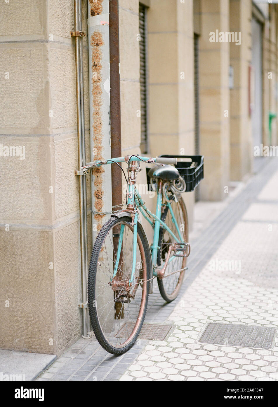 Una vieja bicicleta verde azulado apoyado contra una pared en la ciudad vieja de San Sebastián, España Foto de stock