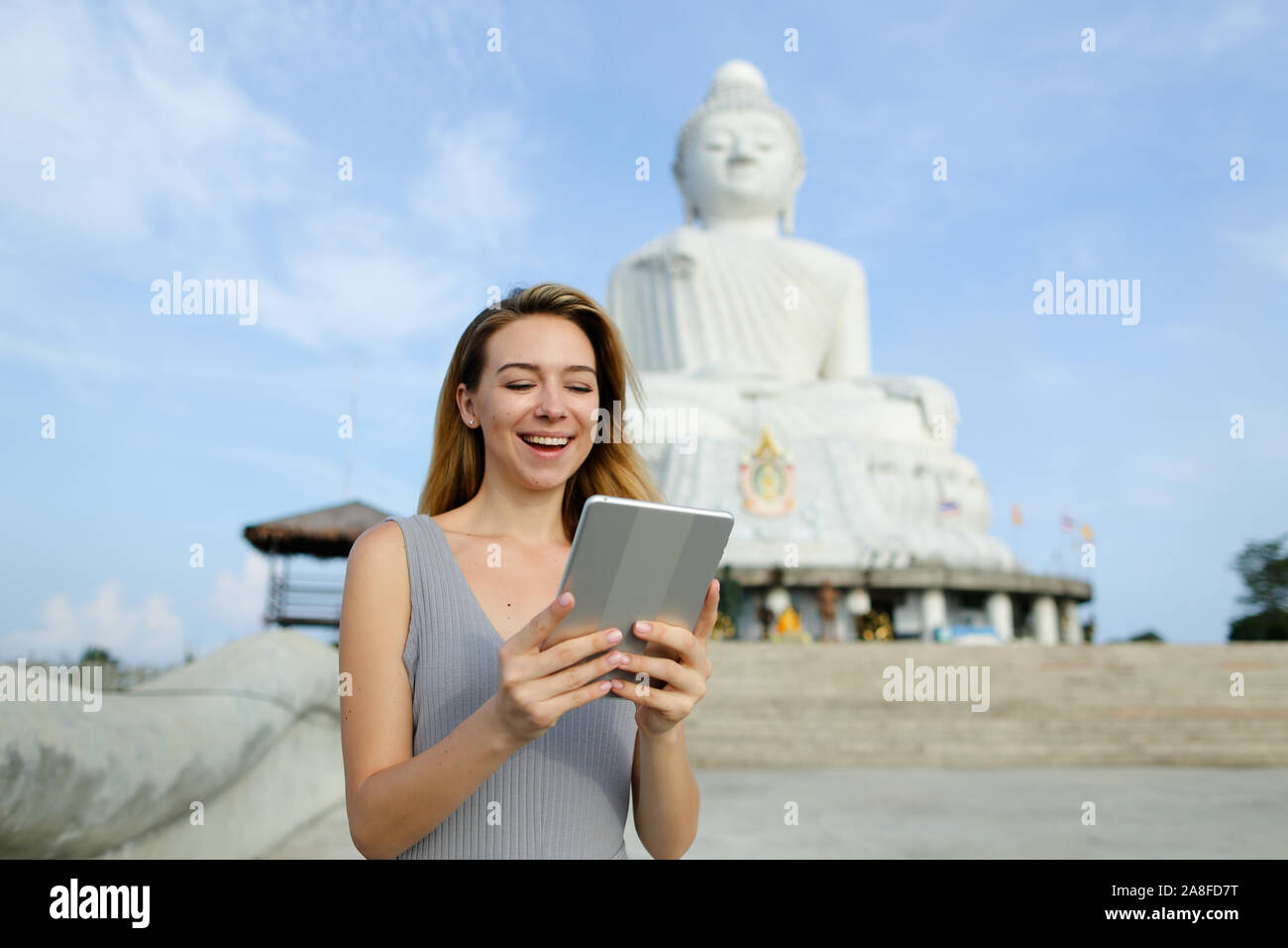 Joven europea utilizando tablet cerca blanca estatua de Buda en Phuket. Foto de stock