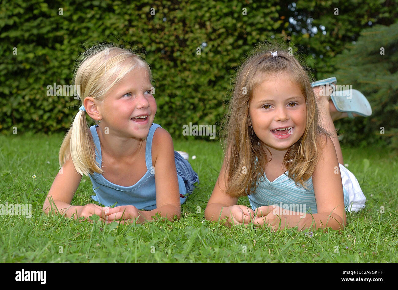 Zwei lachende Kinder liegen im Park auf einer Wiese, Mädchen, 6 Jahre, señor: Sí Foto de stock