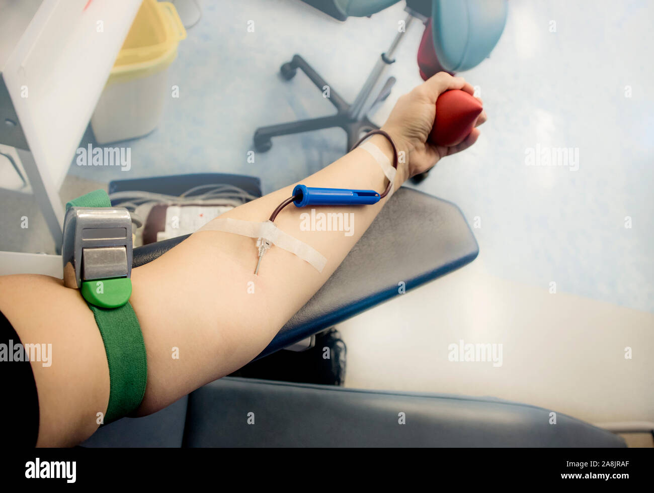 El enfoque selectivo sobre mujer brazo mano con la aguja dentro de la piel, la sangre fluye a través de los equipos de donación de sangre. Feliz mujer positiva de la donación de sangre de donantes c Foto de stock