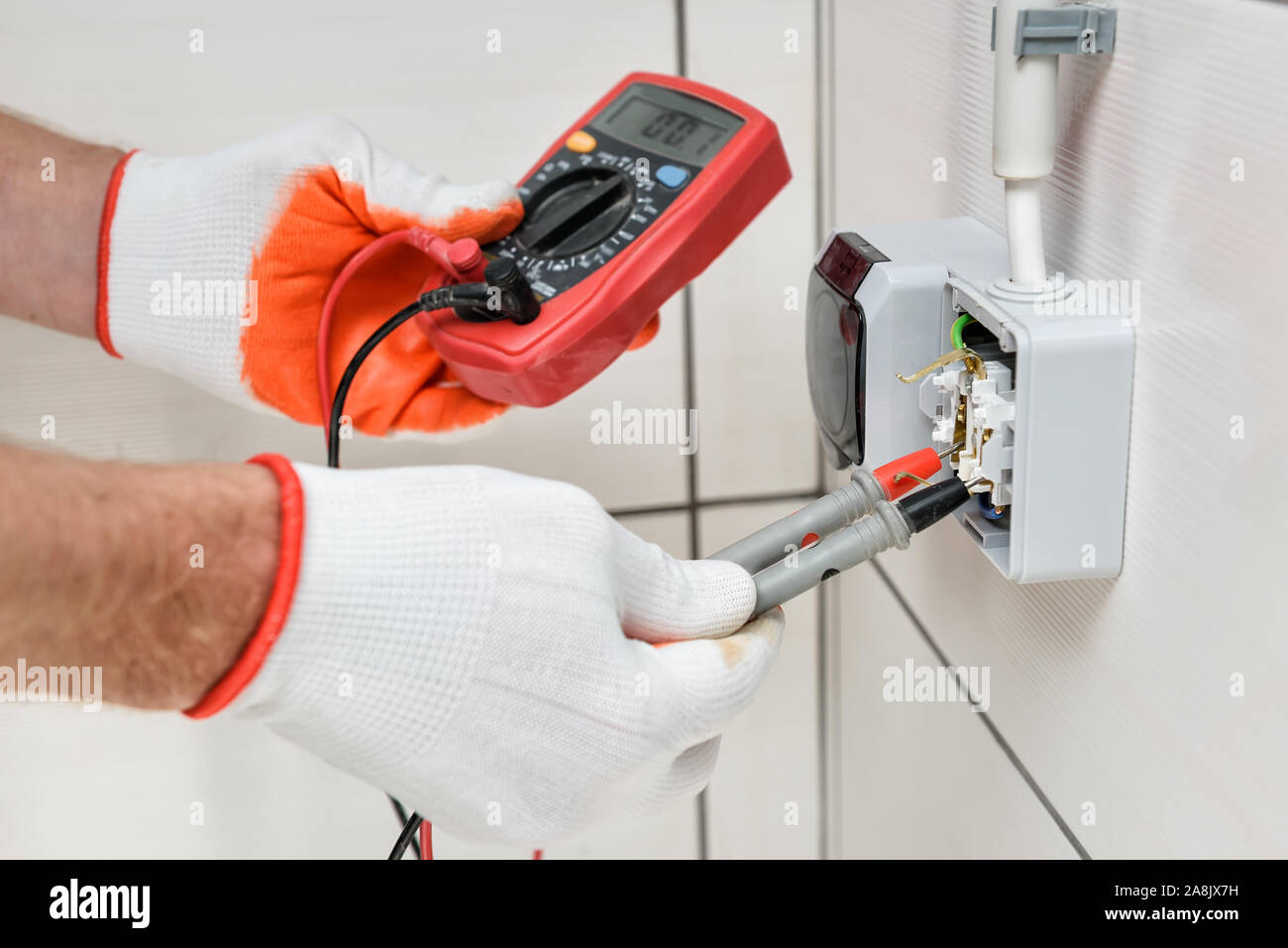 Un electricista es utilizando un multímetro para medir la tensión en un  enchufe de pared Fotografía de stock - Alamy