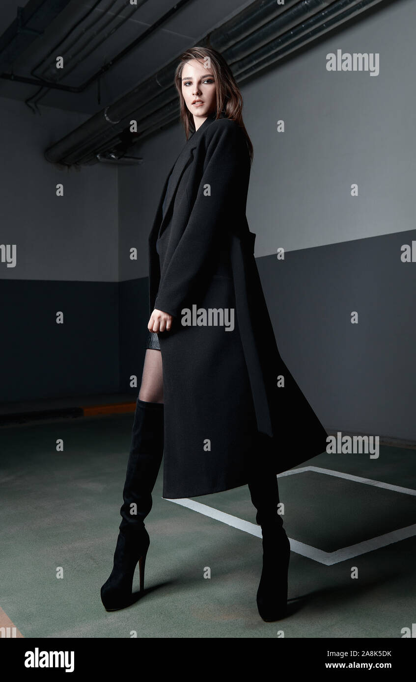 Disparo de moda: retrato de la linda chica vestida de negro de la chaqueta,  falda y botas. Elegante y atractiva mujer joven de pie en el aparcamiento  Fotografía de stock - Alamy