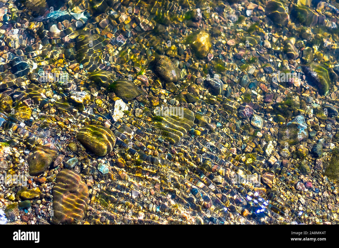 Guijarros de colores brillantes en ondas de agua. Fondo natural orgánica. Foto de stock