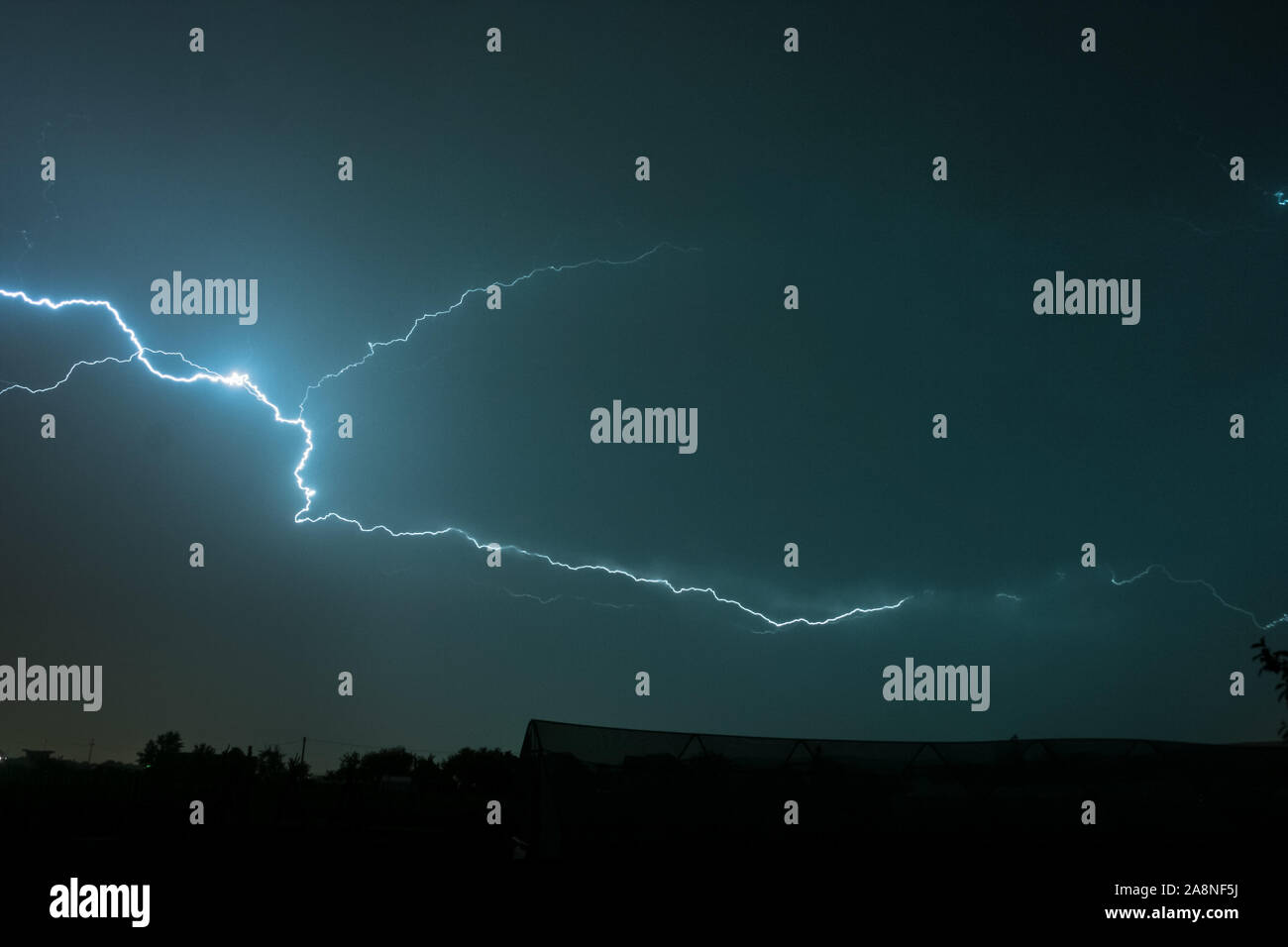 Largo, caprichoso brillante rayo viaja a través de las nubes durante una fuerte tormenta en Europa oriental Foto de stock