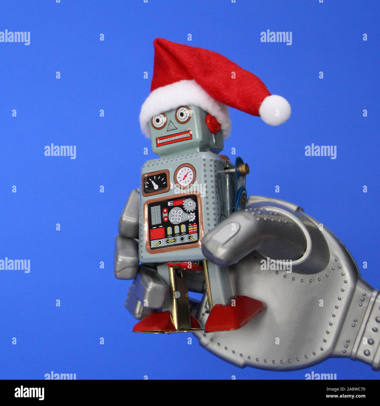 El robot tiene un pequeño robot retro en su mano. El robot tiene un gorro  de Papá Noel. Fiestas de Navidad y Año Nuevo Concepto en el estilo de robots  Fotografía de