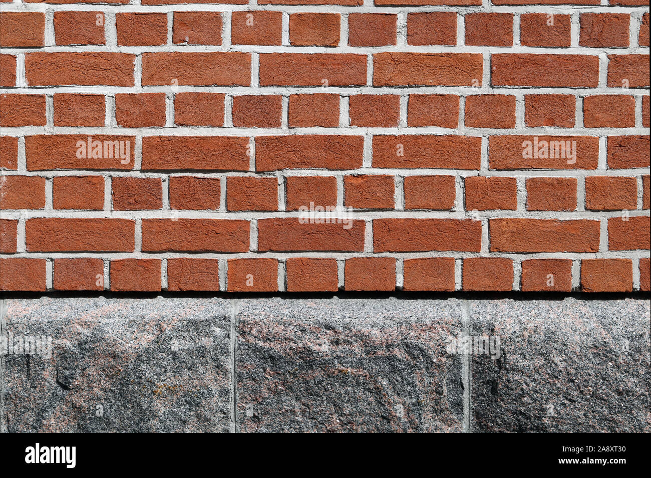 Pared de ladrillo rojo pardusco y pared de piedra gris. La superficie de una pared exterior de un edificio. Precioso y limpio, simétrico detalles arquitectónicos de un edificio. Foto de stock