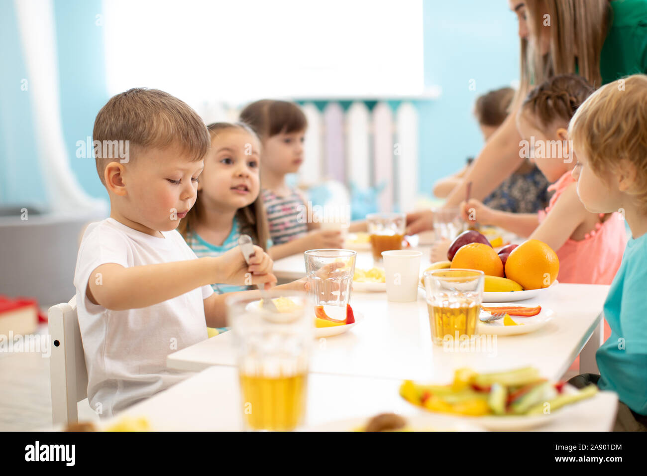 Grupo de niños comiendo en el jardín de infantes o guardería Foto de stock
