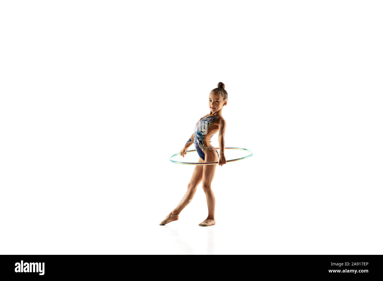 Niña flexible aislada en la pared blanca. pequeña modelo femenina como  artista de gimnasia rítmica en leotardo brillante. gracia en movimiento,  acción y deporte. haciendo ejercicios con la pelota.