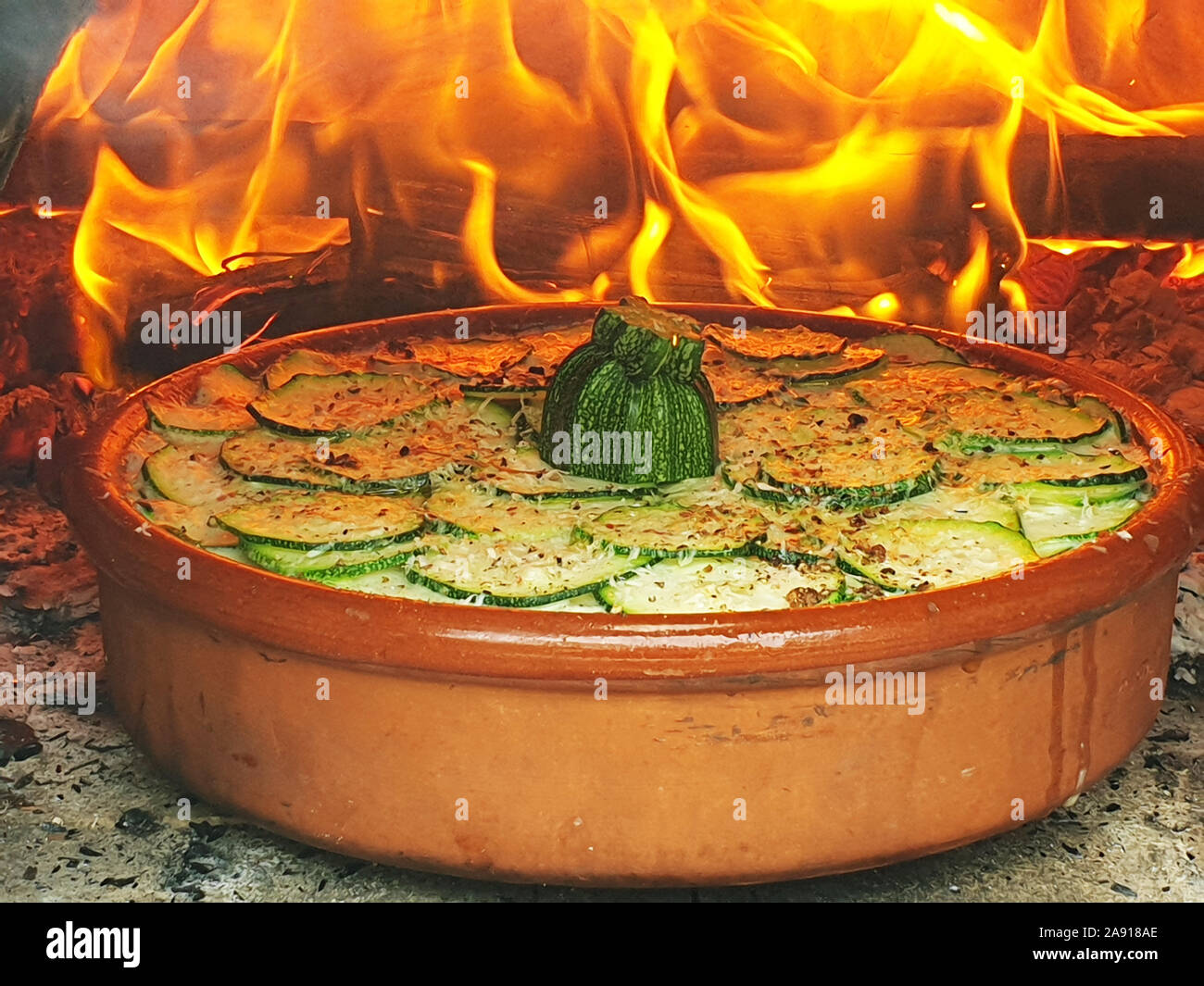 Plato de calabacín en un horno de leña con fuego Foto de stock