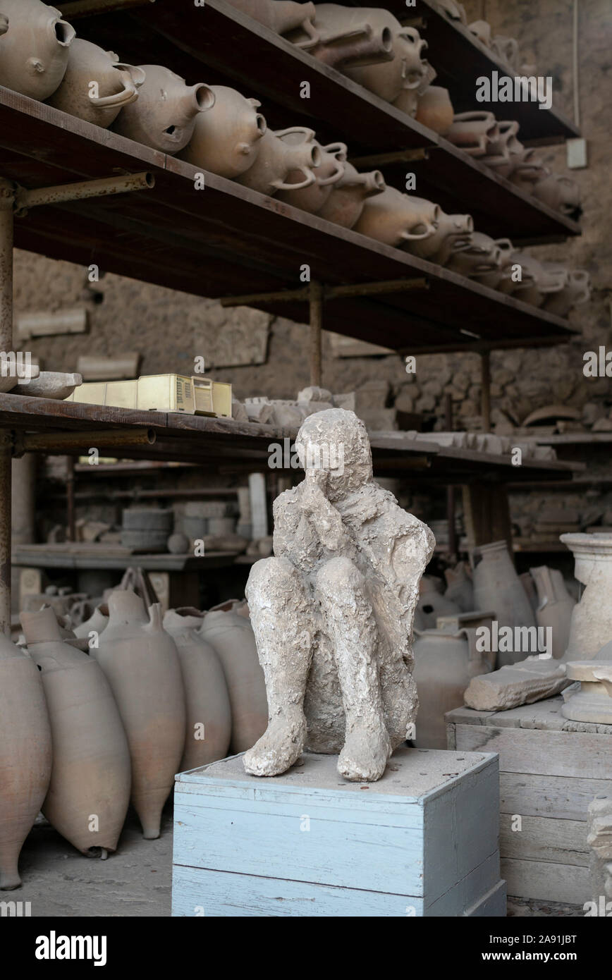 Pompei. Italia. Sitio arqueológico de Pompeya. Yeso de una víctima que murió en la erupción del Monte Vesubio en el año 79 D.C., rodeado de ánforas fo Foto de stock