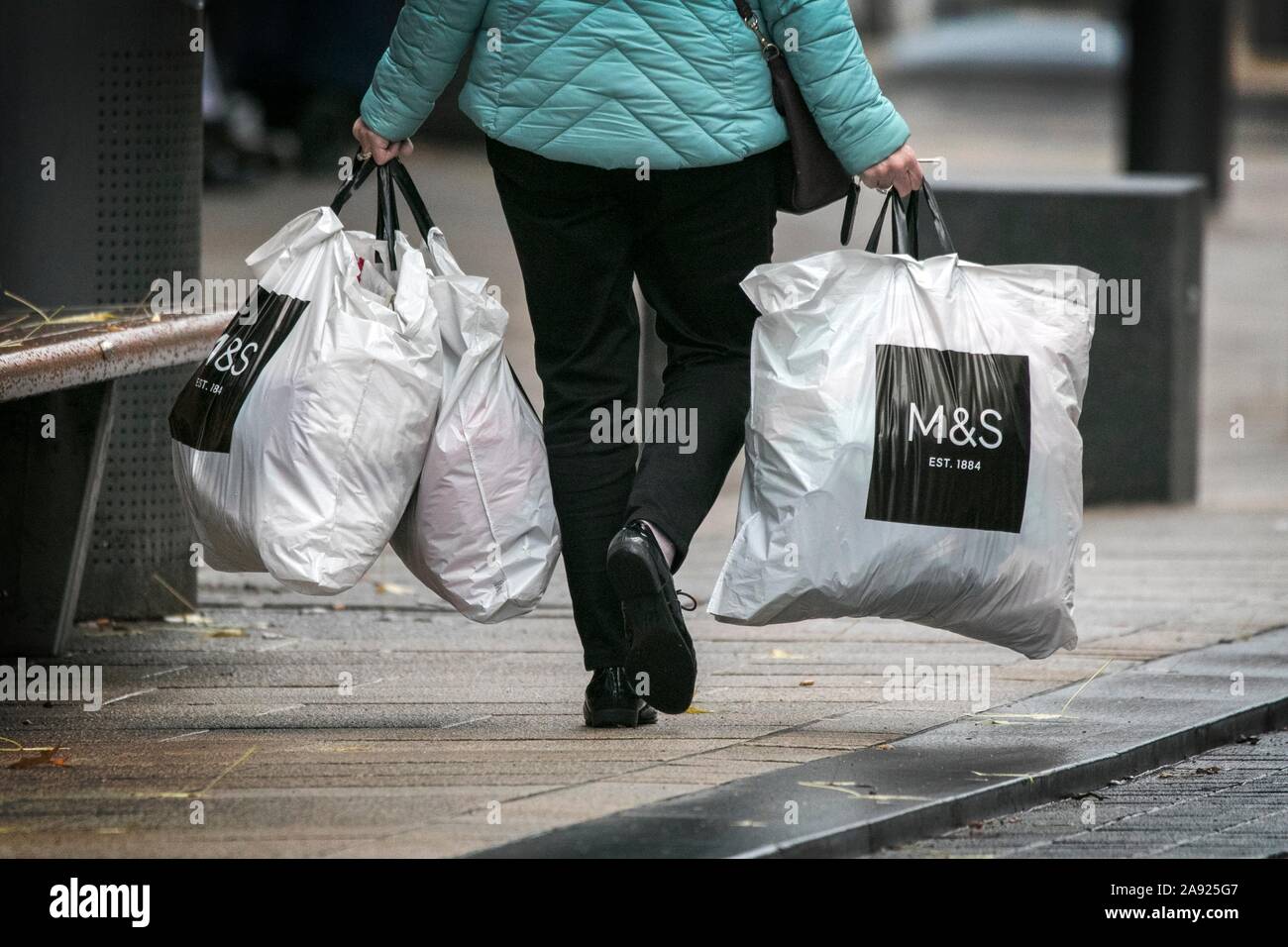 Una mujer que llevaba el M&S Marks & Spencer tienda de ropa bolsas de  plástico 100% reciclado de plástico reutilizables bolsas de supermercados  de por vida Fotografía de stock - Alamy