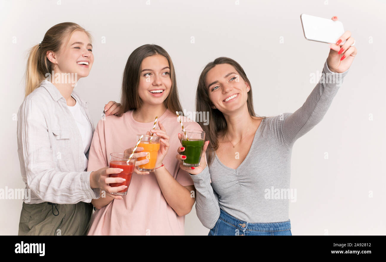 Las niñas haciendo selfie con cócteles de desintoxicación y sonriendo ampliamente Foto de stock