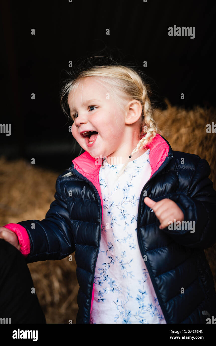 Una niña divirtiéndose en una colina de heno Foto de stock