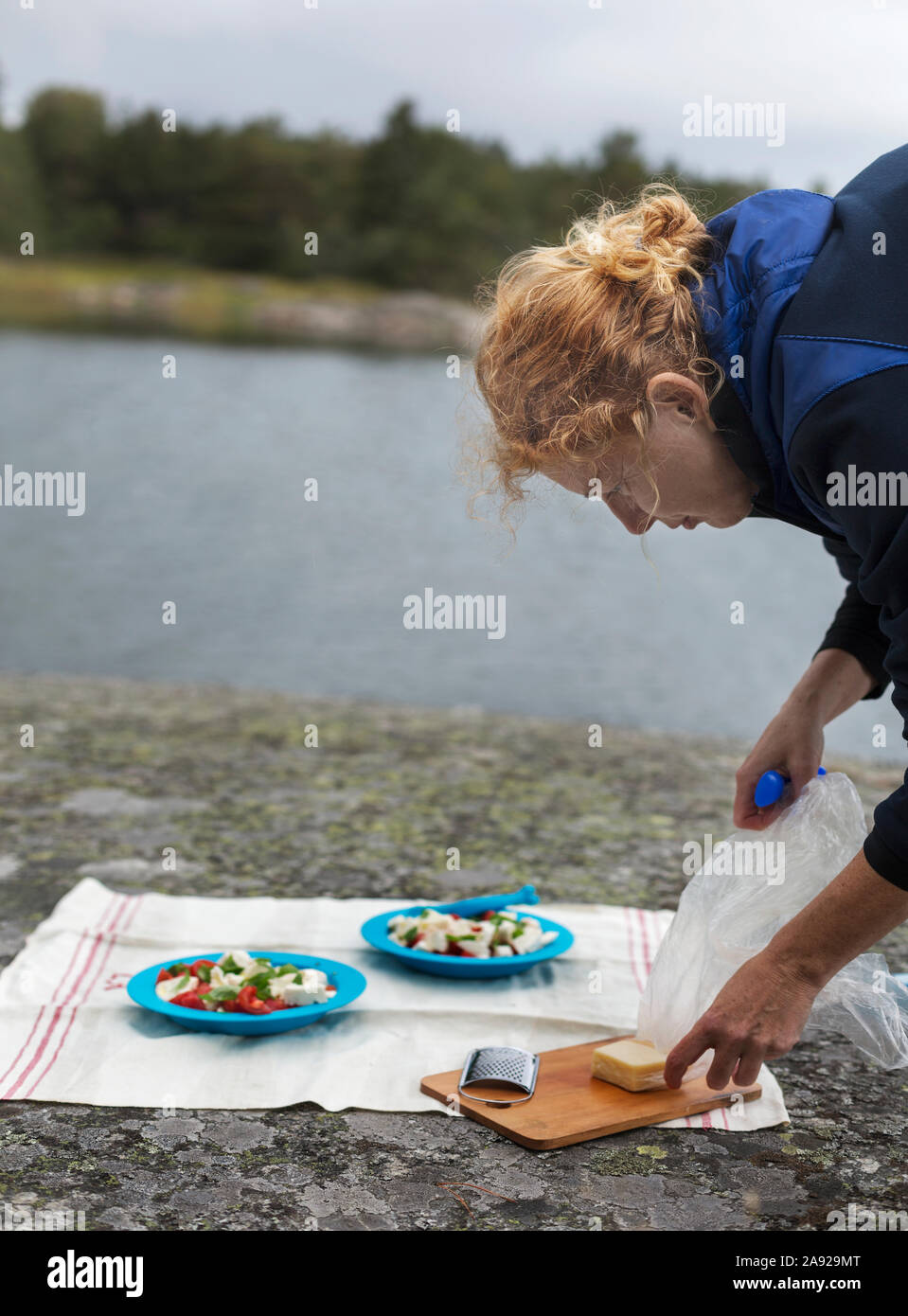 Mujer preparando para cenar al aire libre en roca Foto de stock