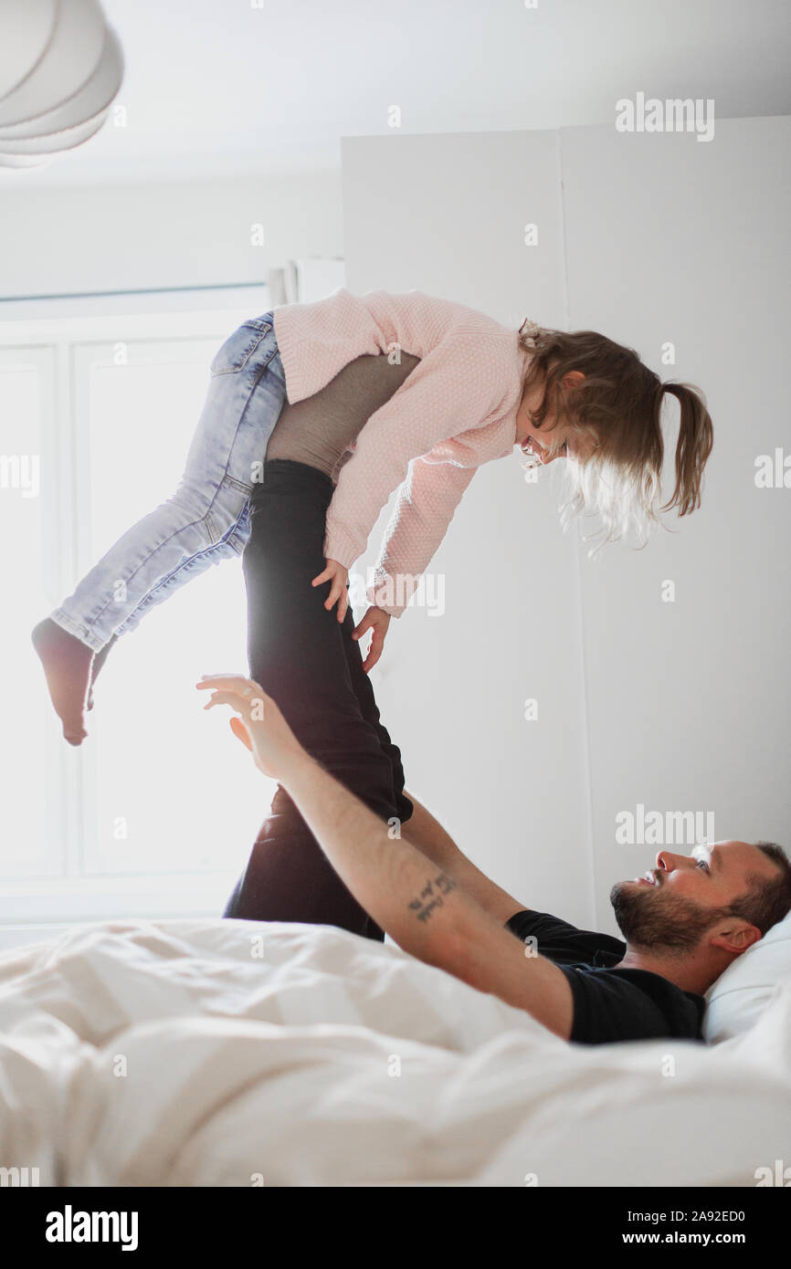 Padre jugando con su hija en la cama Foto de stock