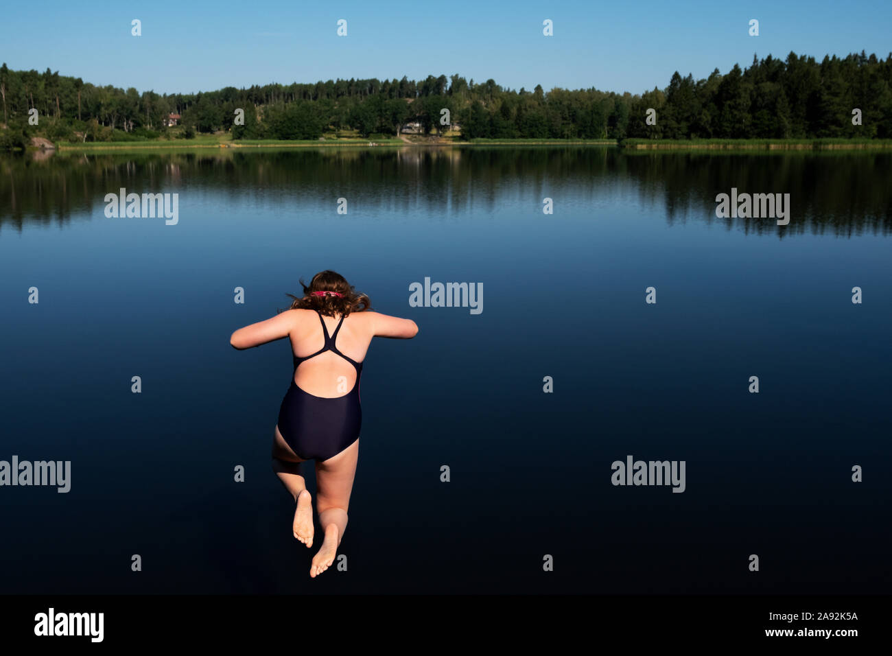 Chica saltar en el lago Foto de stock