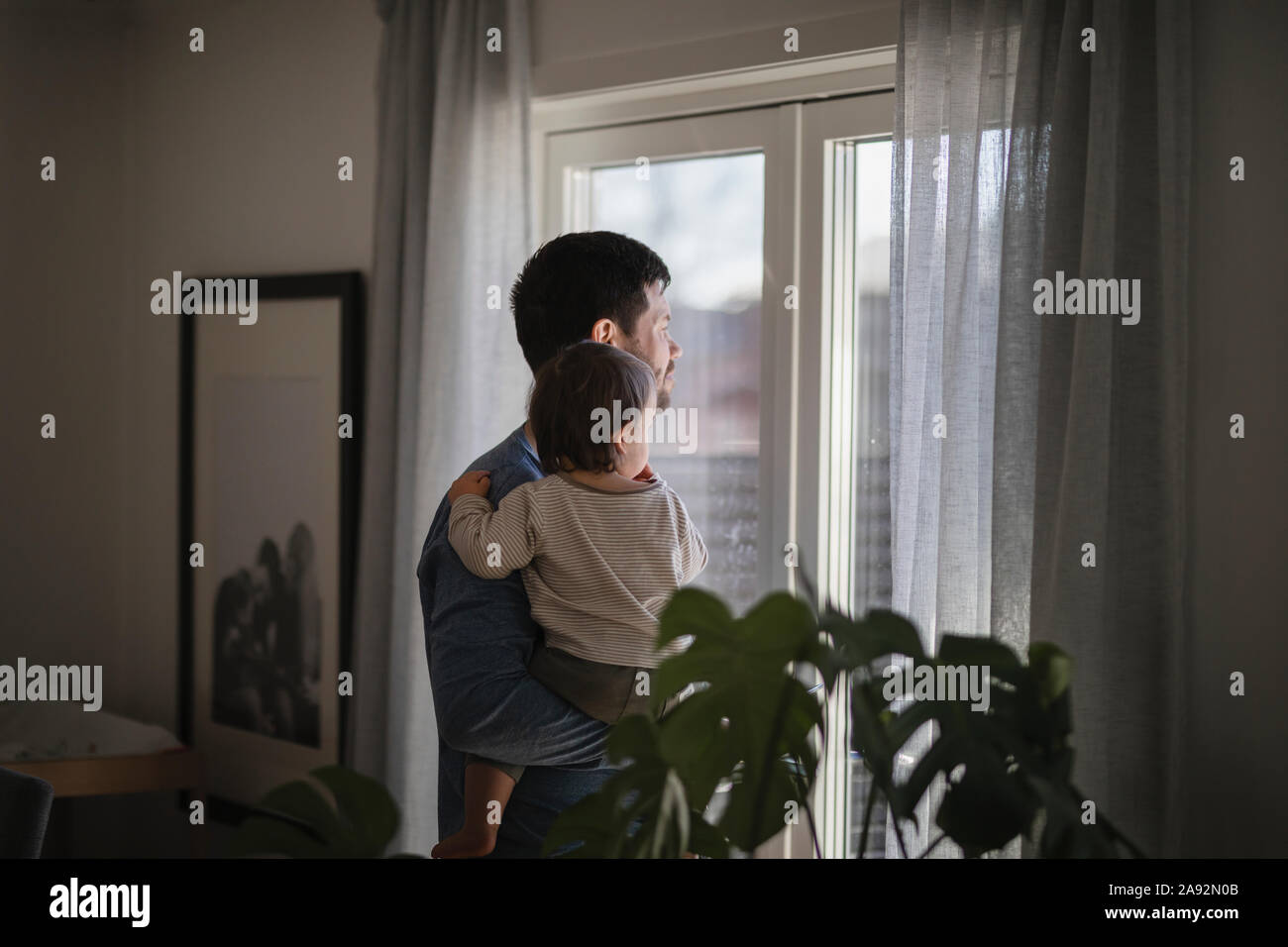 El padre con el bebé mirando a través de la ventana Foto de stock