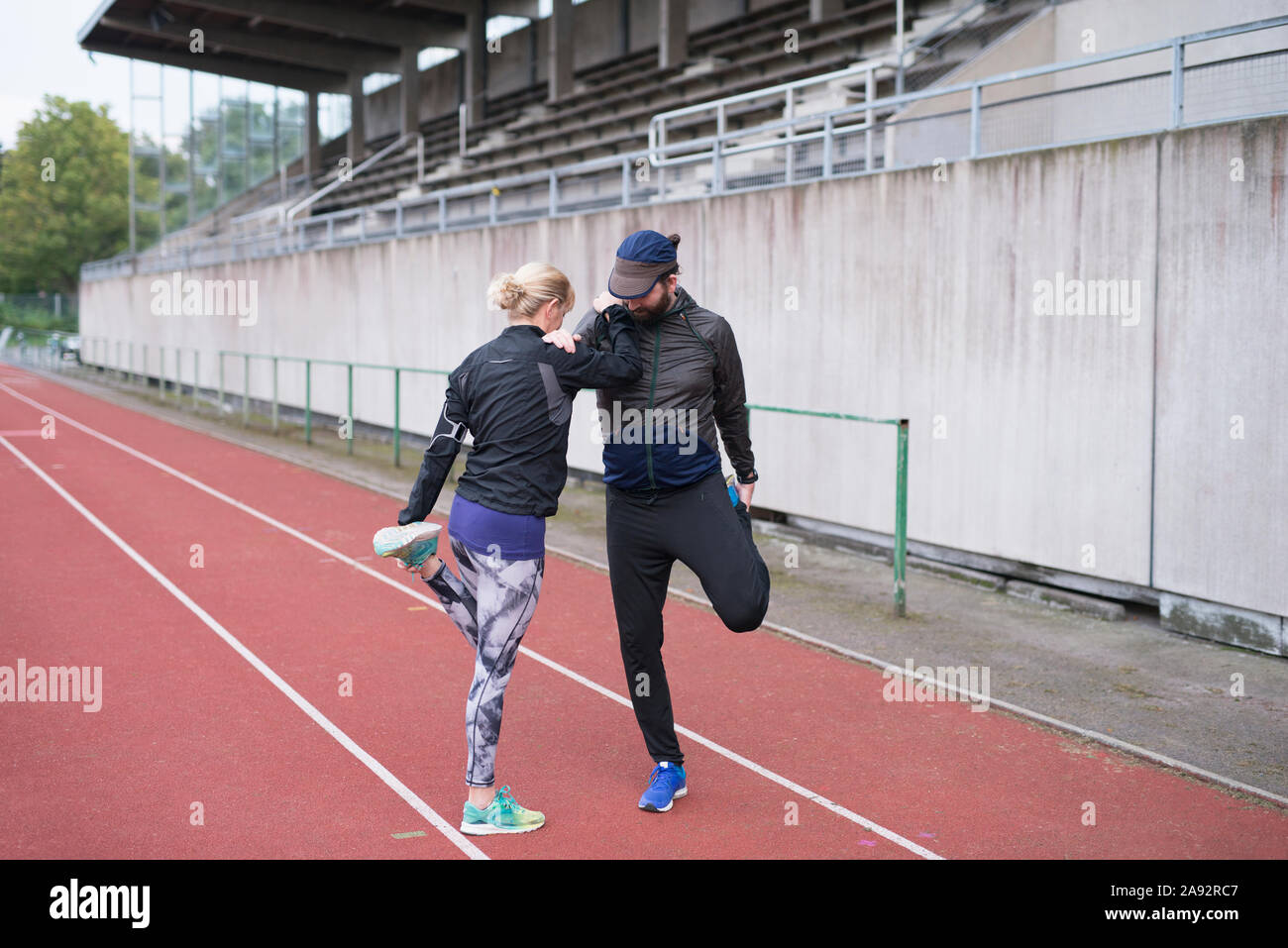 El hombre y la mujer en la pista de atletismo de estiramiento Foto de stock