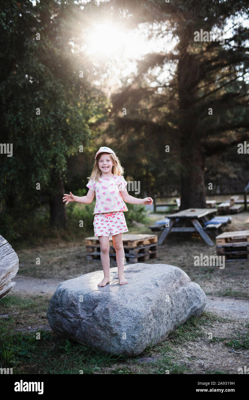 Chica sonriente de pie sobre una roca Foto de stock