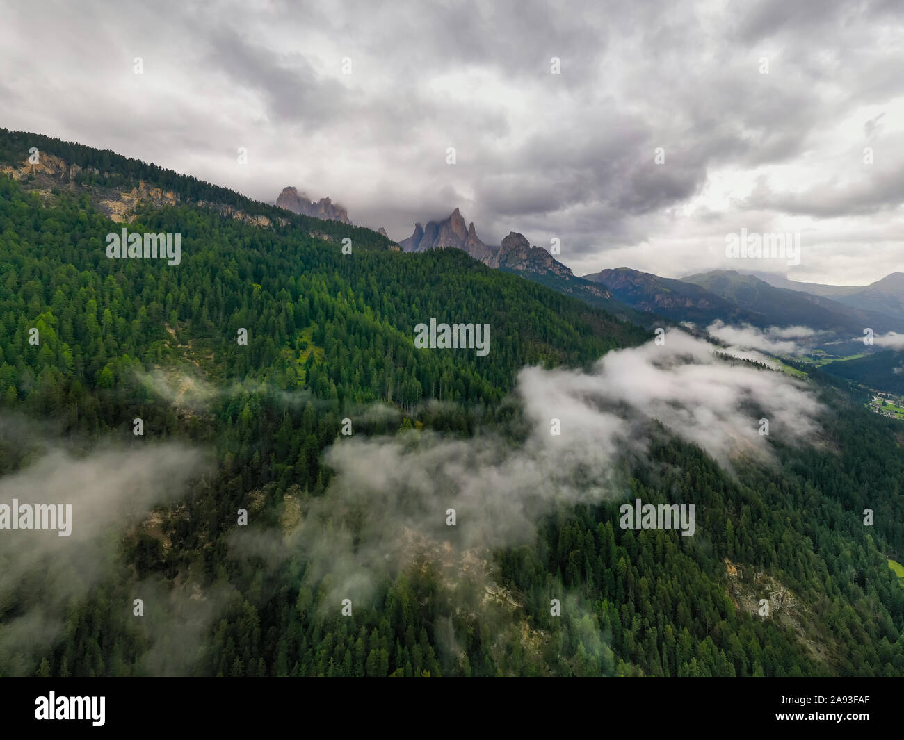 Antena de hermosas vistas panorámicas de los Alpes Dolomitas, Italia. Montañas cubiertas de nubes y niebla. Catinaccio cordilleras. El valle de Val di Fassa, Foto de stock