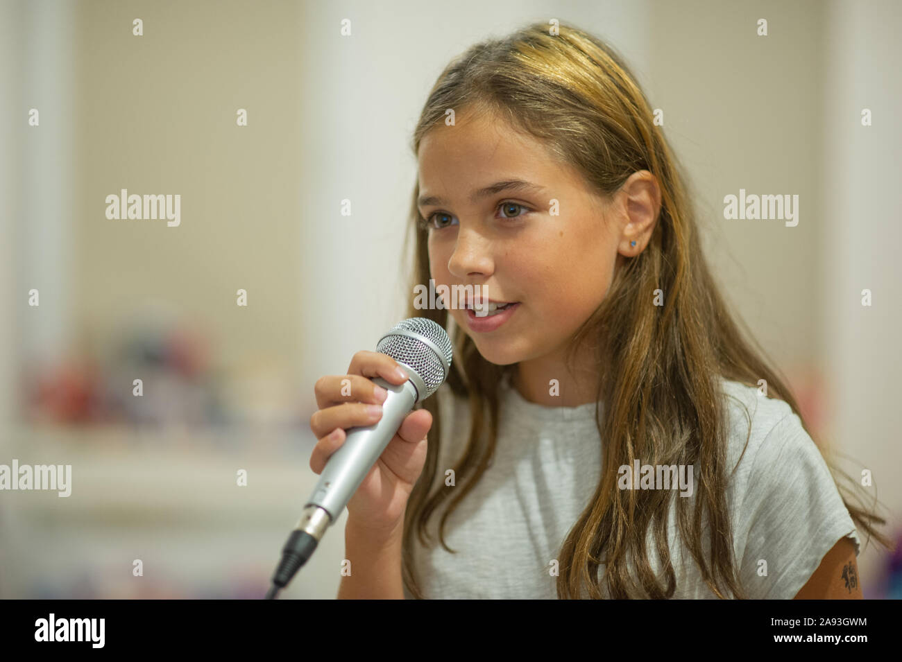 Sinceramente amplitud Motivar Muchacha con micrófono en fondo blanco. Chica canta Karaoke. Una niña de  10-11 años emocionalmente canta en un micrófono. Karaoke casero. M  Fotografía de stock - Alamy