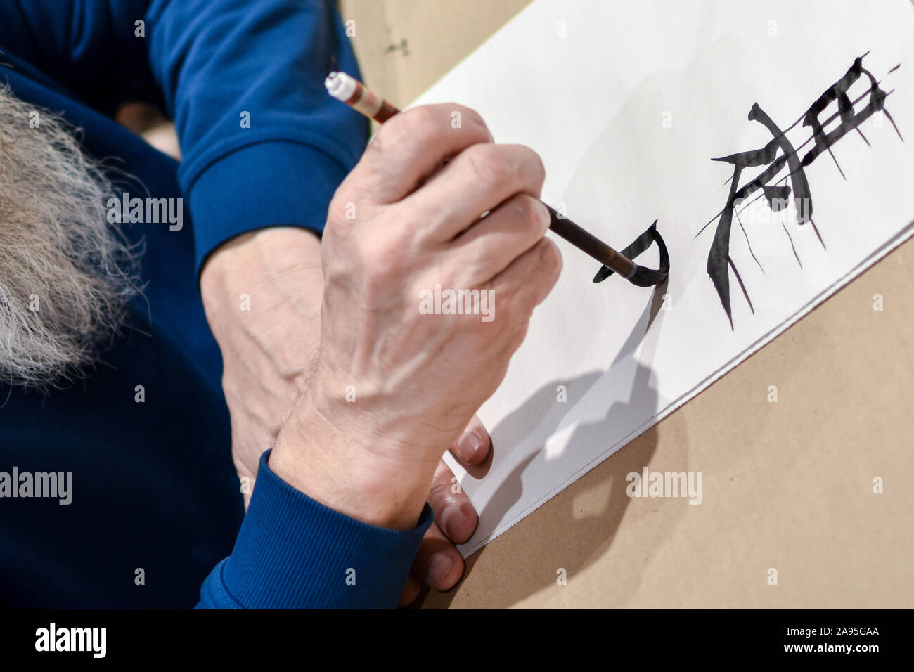 Maestro de caligrafía china dibujo jeroglífico con una brocha. Foto de stock