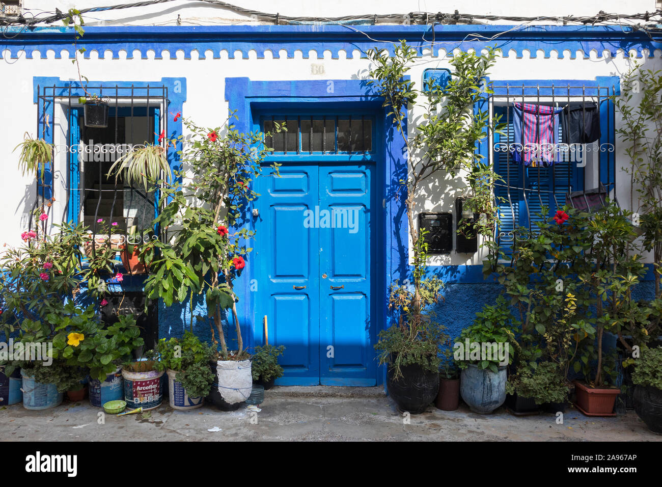 Asilah, Morocco-September 10, 2019: la fachada de una casa tradicional con una puerta pintada de azul y plantas en macetas en la medina de Asilah, Marruecos Foto de stock