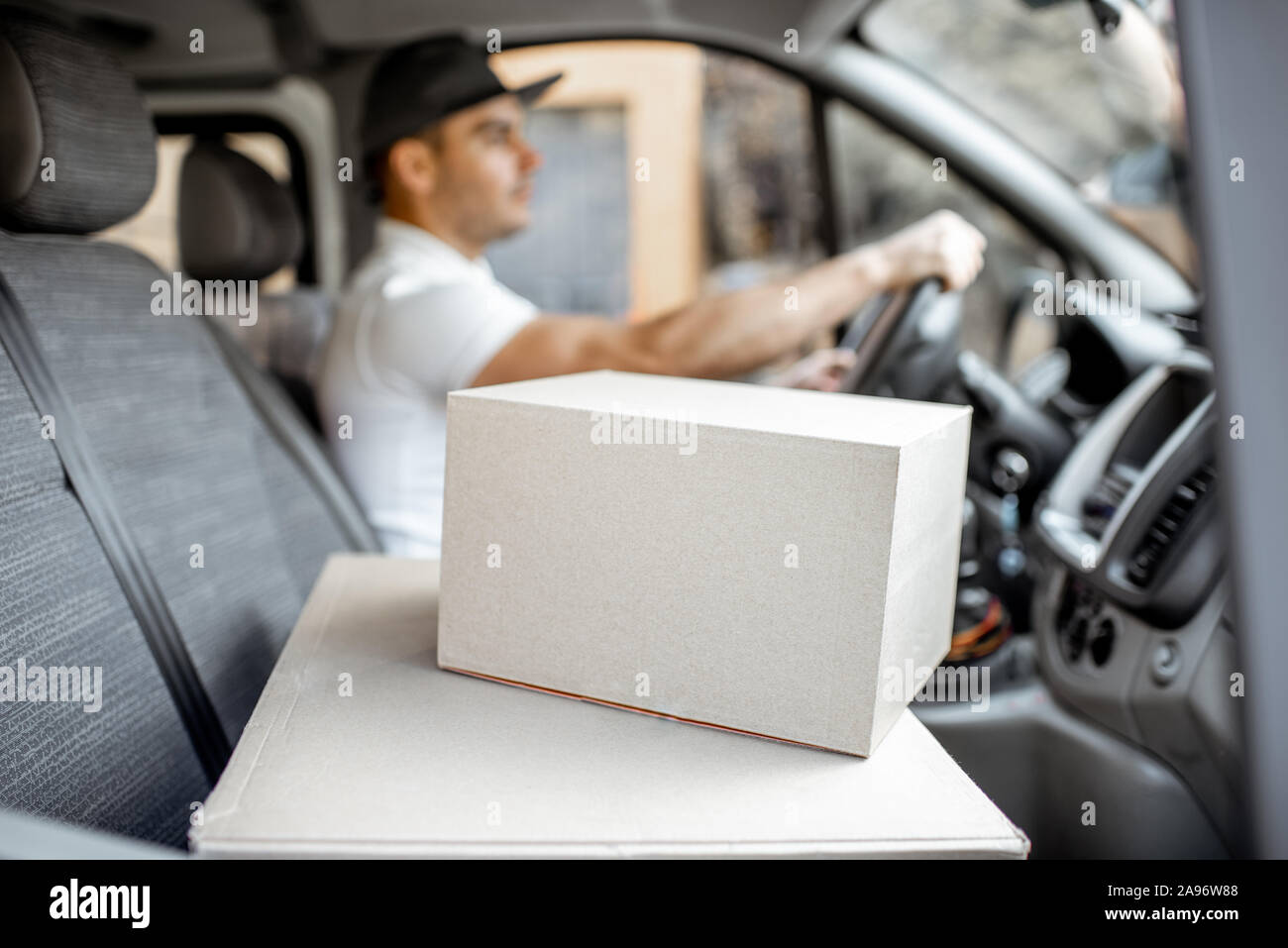 Hombre de entrega de conducción de vehículos de carga con bultos en el asiento del pasajero, imagen centrada en las cajas de cartón con espacio en blanco Foto de stock