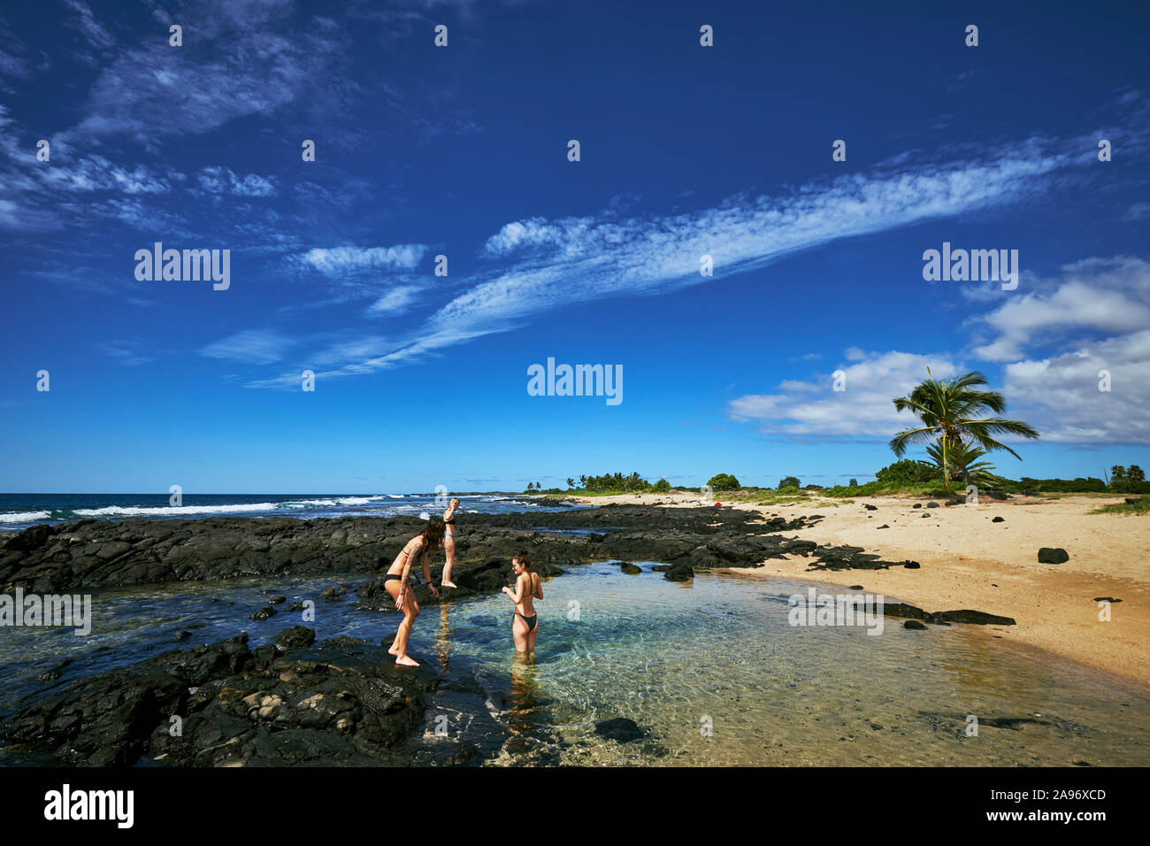 Tres mujeres jugando en una piscina natural en la Isla Grande de Hawai Foto de stock