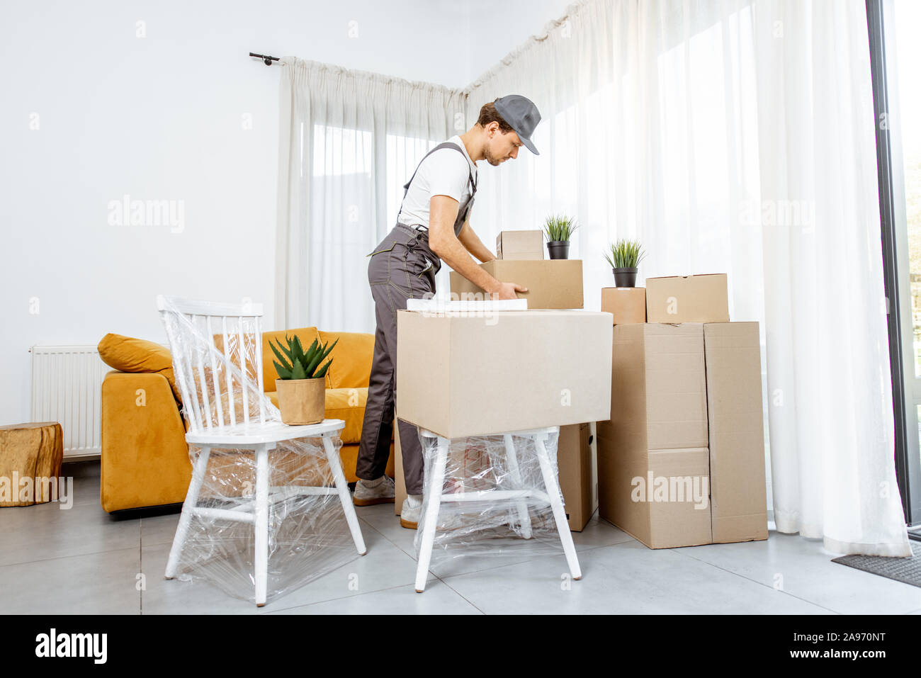 Guapo promotor de ropa de trabajo profesional realizando la entrega de una  mercancía y muebles durante el proceso de traslado a una nueva casa, vista  interior Fotografía de stock - Alamy