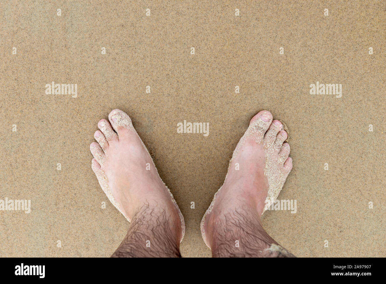 Pies masculinos arena de playa vacaciones vacaciones húmedo de mediana edad conseguir unas piernas suaves dedos Foto de stock