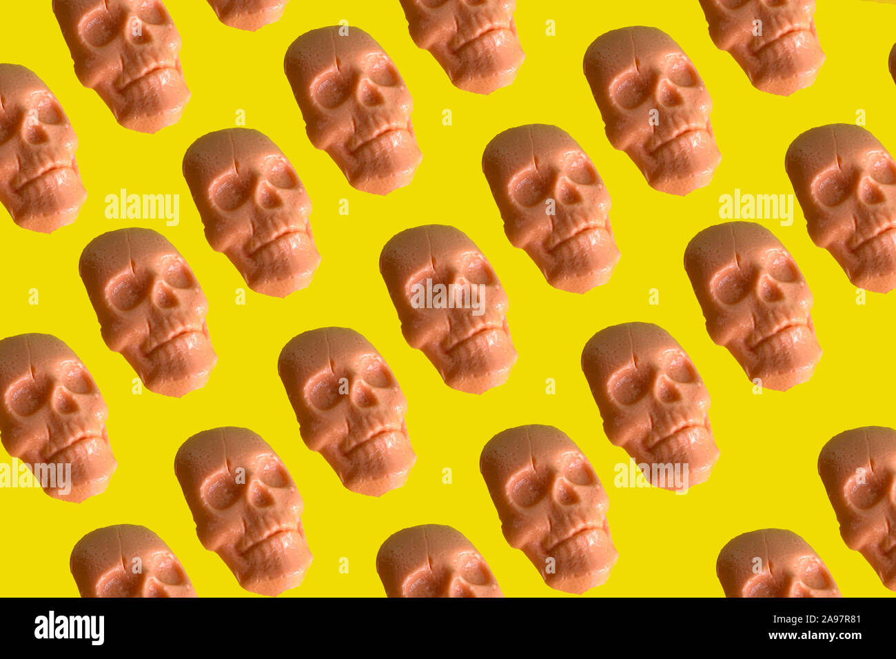 Cráneo humano con forma de caramelo patrón sobre fondo amarillo vibrante Foto de stock