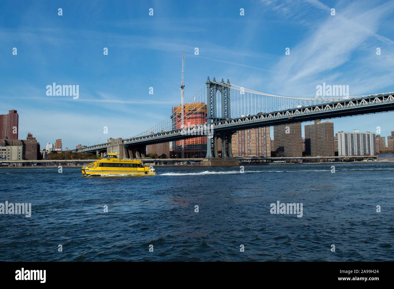 Water taxi amarillo que navegan bajo Manhattan Bridge -NY Foto de stock