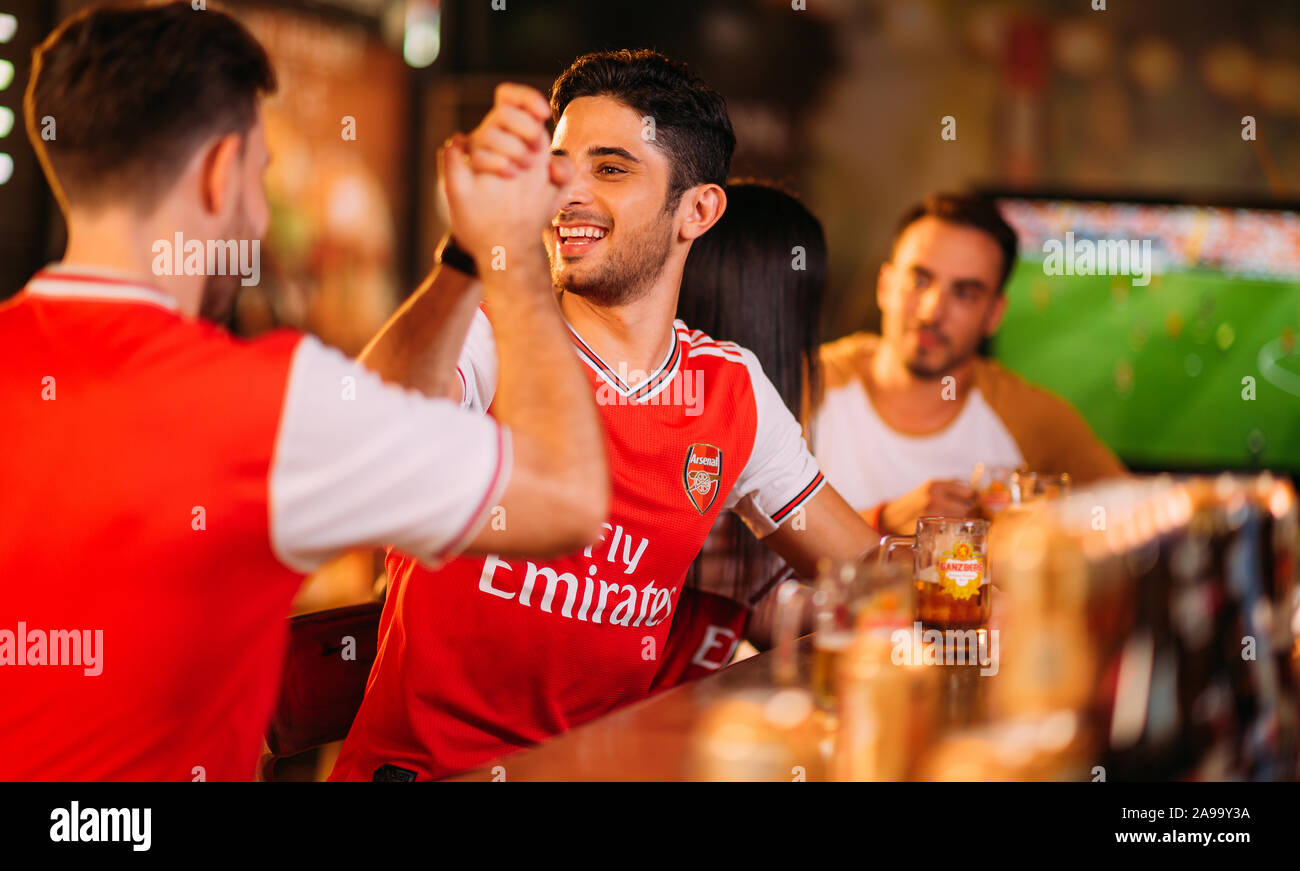 Aficionados al arsenal de la fiesta entusiasmados viendo el fútbol con Ganzberg Beer in el pub Foto de stock