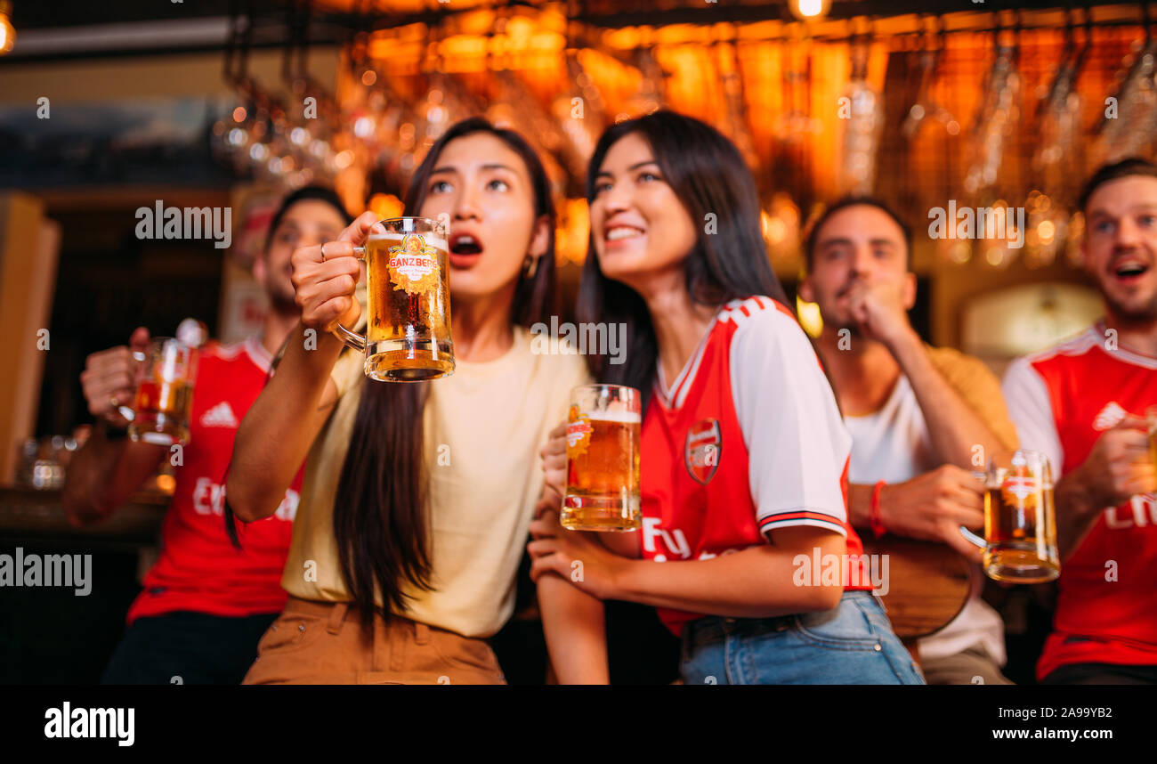 Aficionados al arsenal de la fiesta entusiasmados viendo el fútbol con Ganzberg Beer in el pub Foto de stock