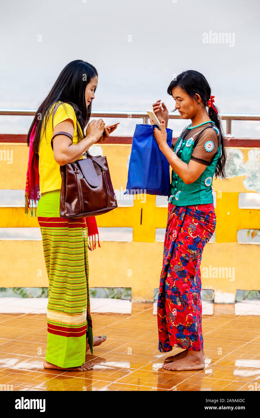Dos mujeres usando sus teléfonos móviles (celulares) fuera de la Su Taung Pyae Pagoda, Mandalay Hill, Mandalay, Myanmar. Foto de stock