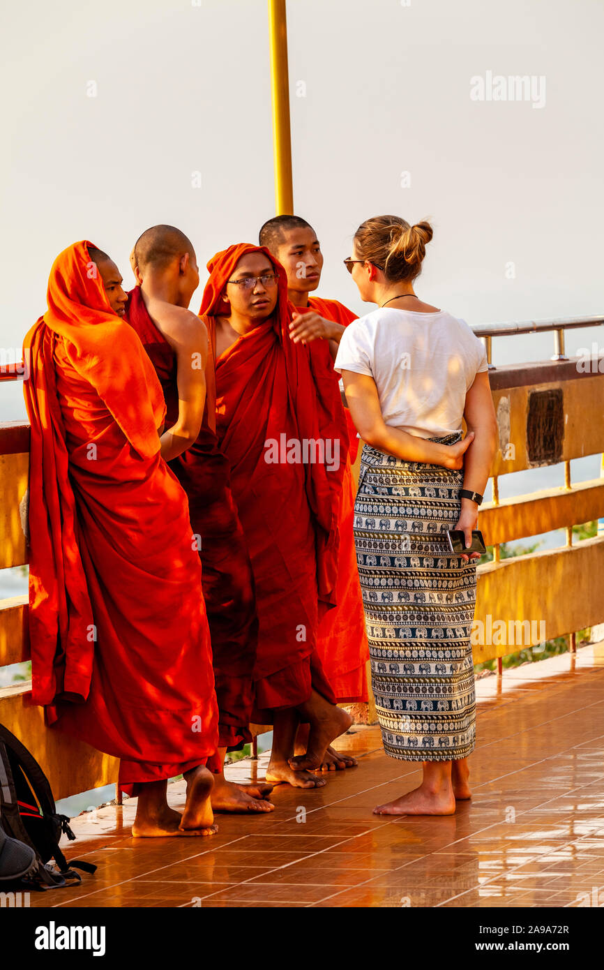 Un turista femenina charlas a un grupo de monjes budistas, Su Taung Pyae Pagoda, Mandalay Hill, Mandalay, Myanmar. Foto de stock