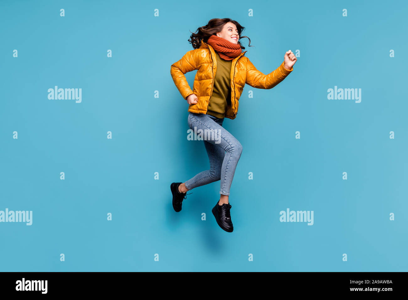 Foto de longitud completa loco dama milenario saltar la velocidad de funcionamiento alta temporada de compras descuentos desgaste Cortavientos elegante bufanda jeans pullover aislado Foto de stock