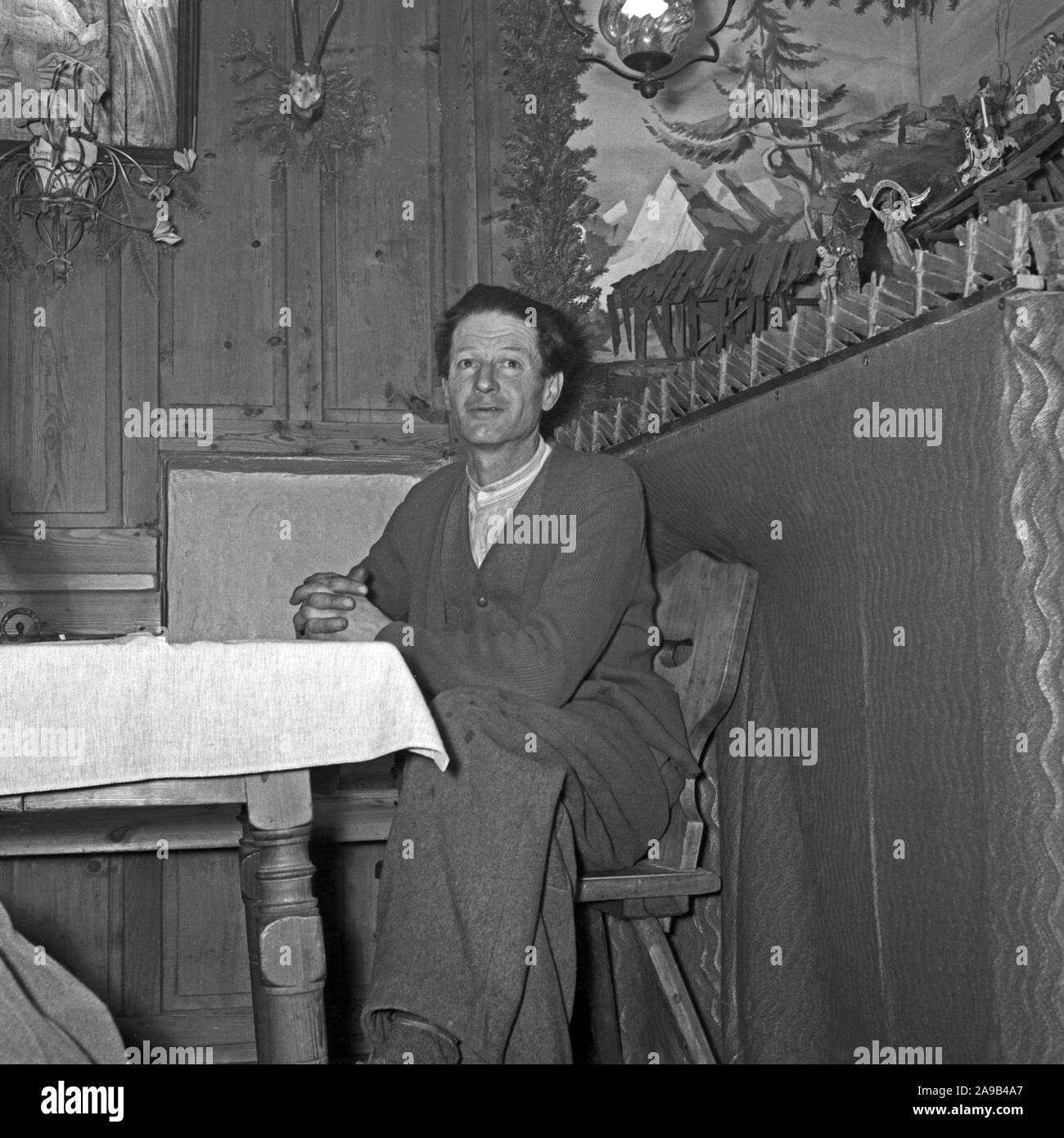 Un hombre sentado en una mesa esperando la Navidad, Alemania 1955 Foto de stock