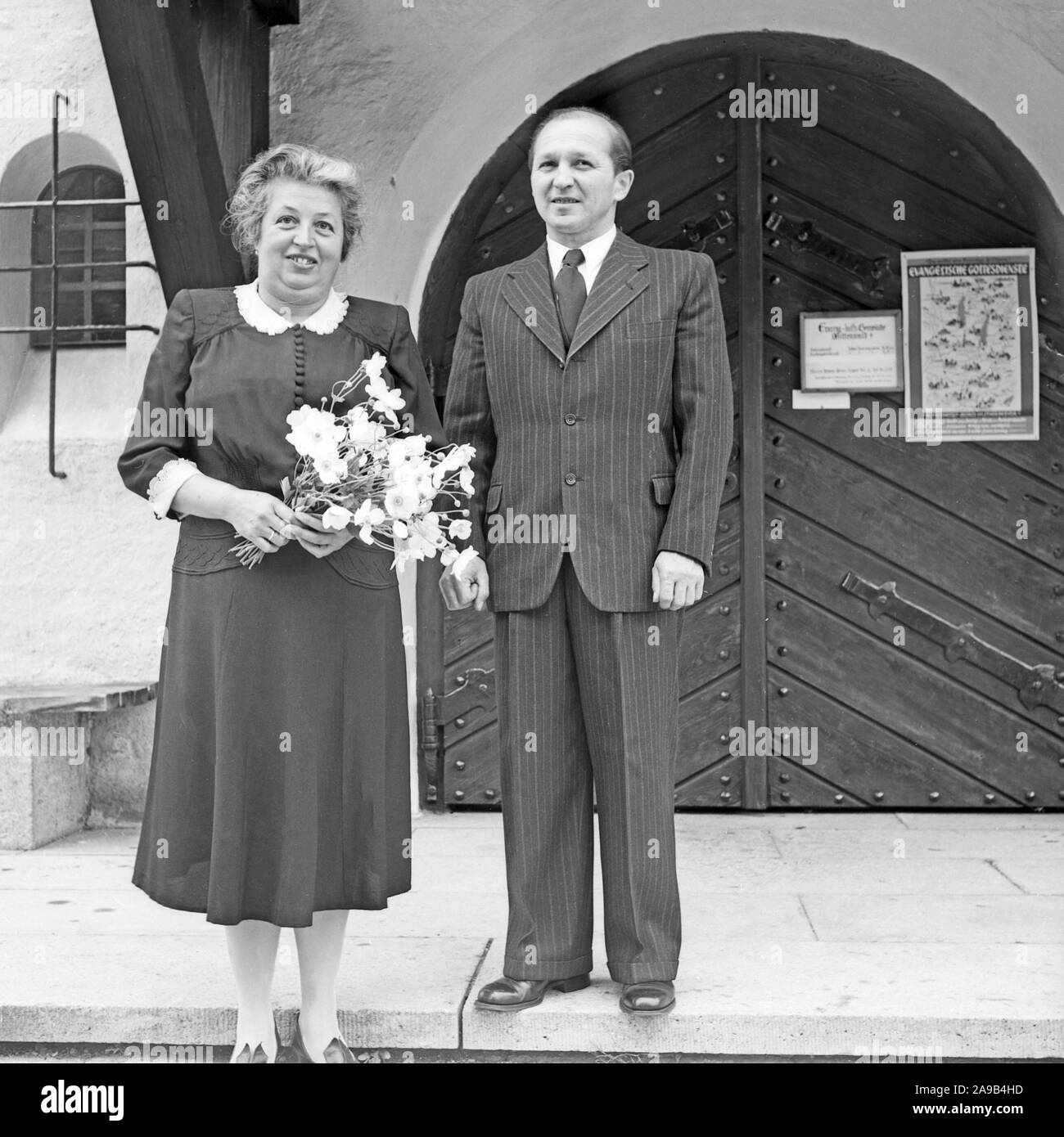 Una pareja de ancianos de pie en la puerta de una iglesia protestante, Alemania 1959 Foto de stock