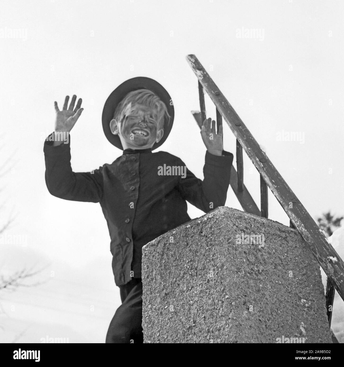 Un chico jugando el chimney sweeper como símbolo de buena suerte para el año nuevo, Alemania 1955 Foto de stock