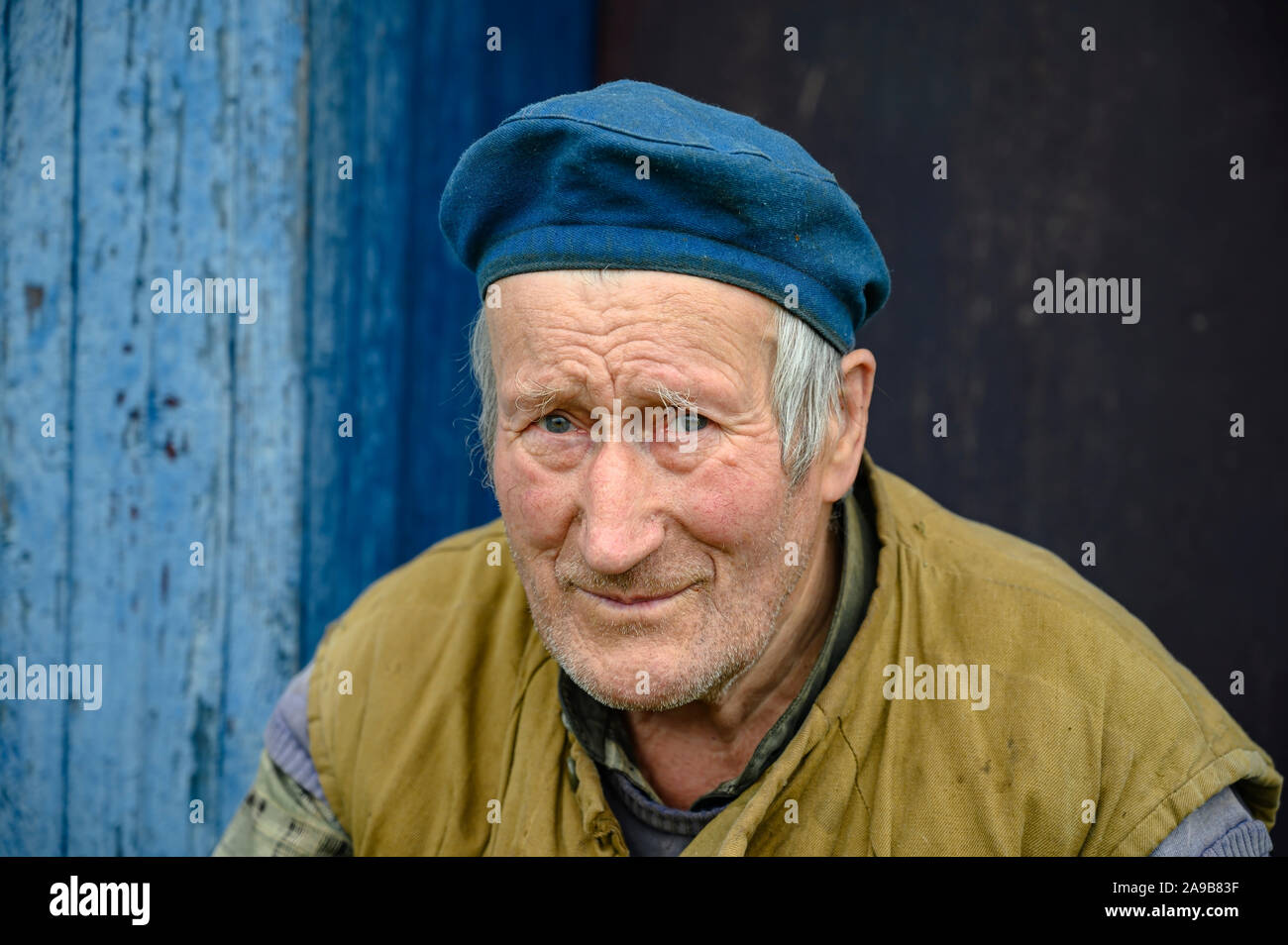 Retrato de un hombre anciano en una boina el porche de una casa de Fotografía de stock -