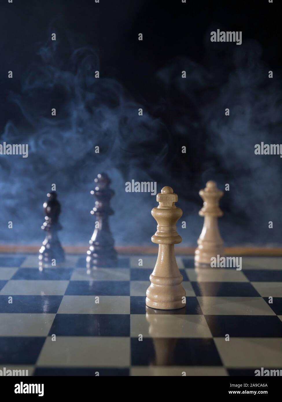 Concepto del juego de tablero de ajedrez de la batalla, la guerra y la  estrategia. Figuras de ajedrez sobre un fondo oscuro con humo y niebla.  Enfoque selectivo Fotografía de stock -