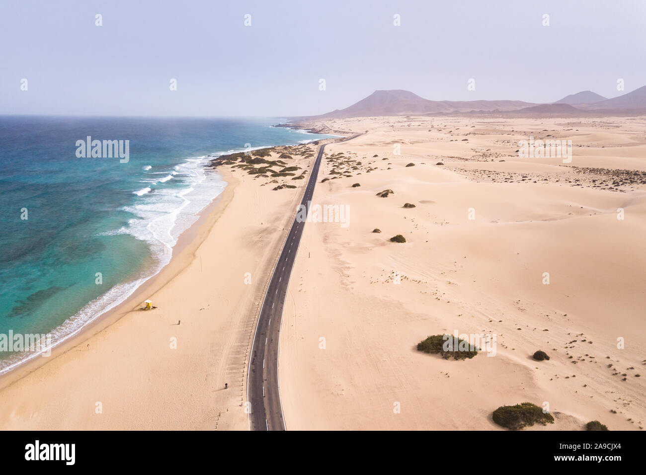 Vista aérea de playa con una carretera que bordea la costa del océano y dunas de arena en Fuerteventura, Islas Canarias, visto desde el drone, pintorescos paisajes costeros, verano Foto de stock